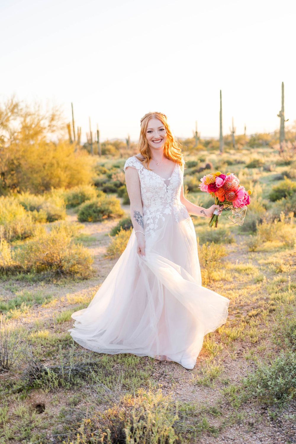Wedding fashion photo in desert landscape with flowing white dress and bright bouquet.