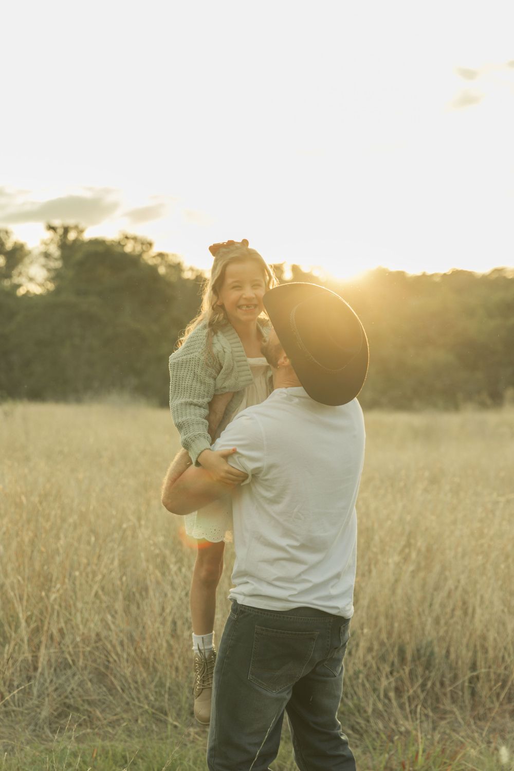 Candid family moments captured in a sun-drenched field at dusk.