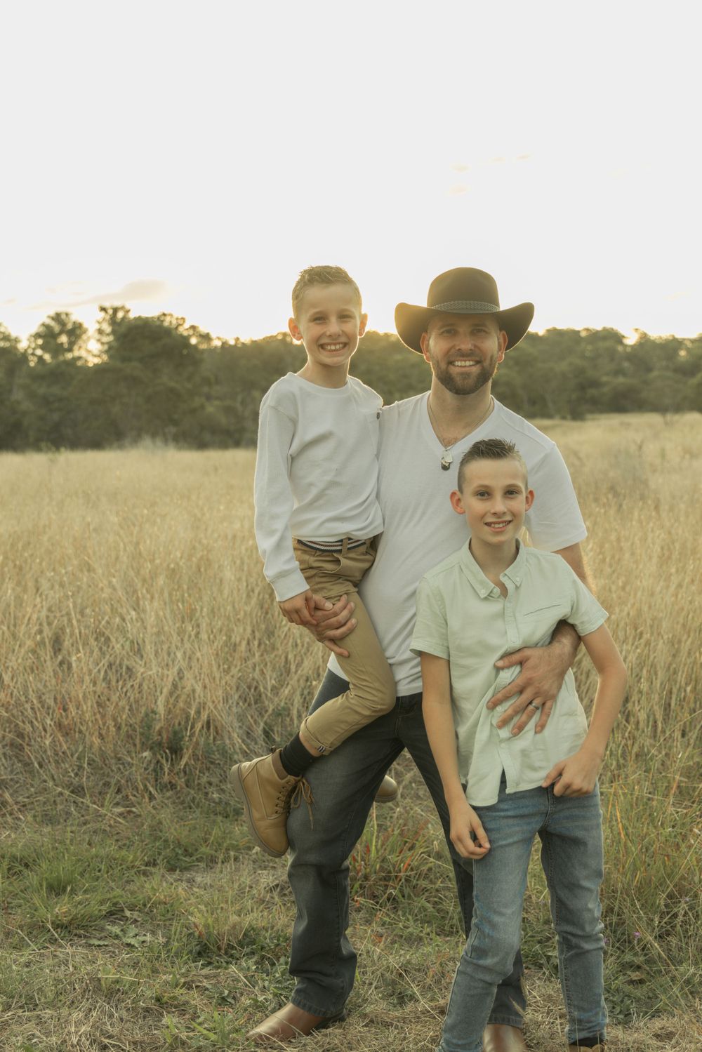 Joyful interactions between father and sons in an outdoor setting during sunset.