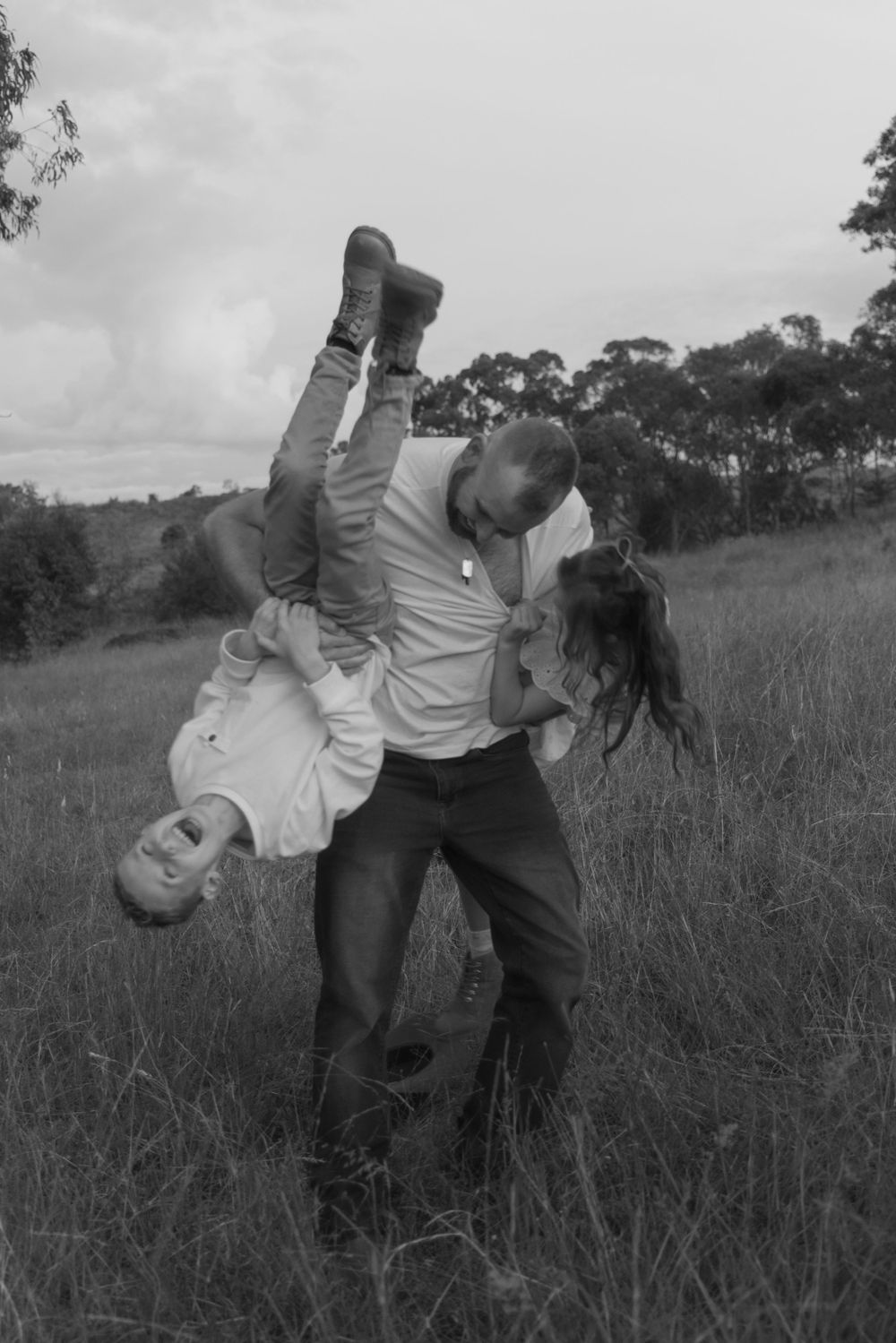 A playful photo sequence capturing children being dipped by father backwards in a grassy field at sunset.
