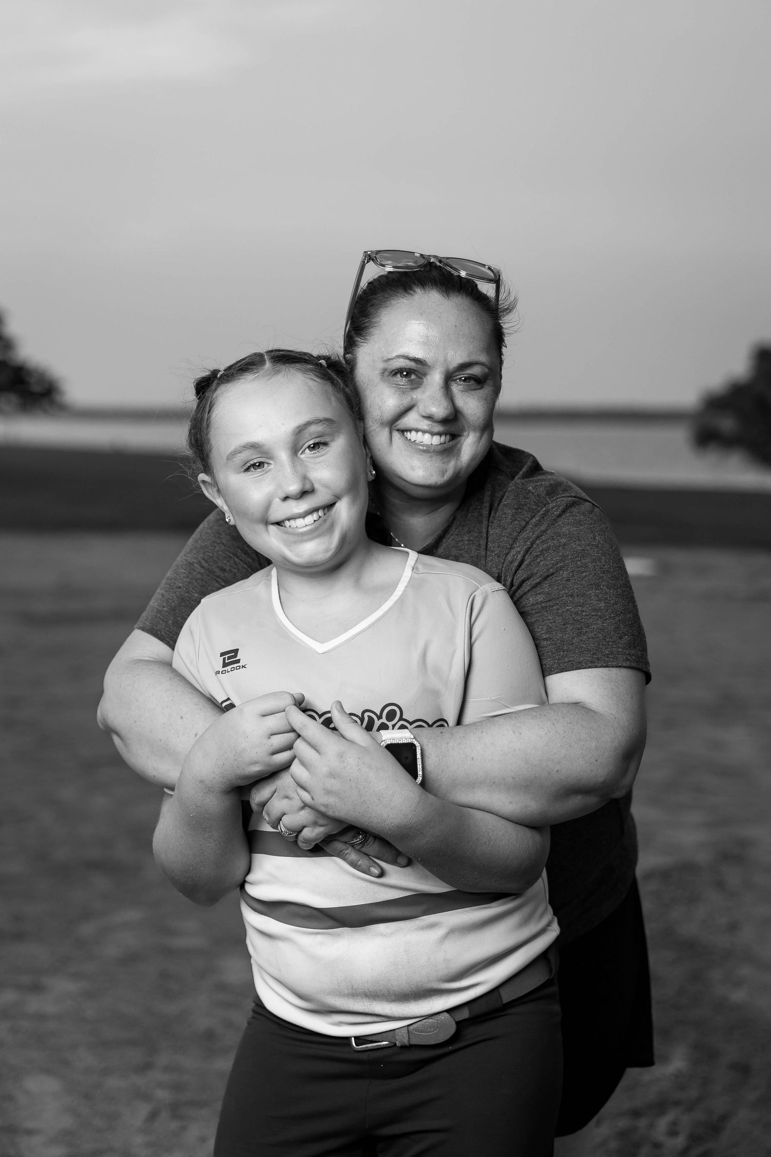 Heartwarming embrace captured in black and white on outdoor sports field.