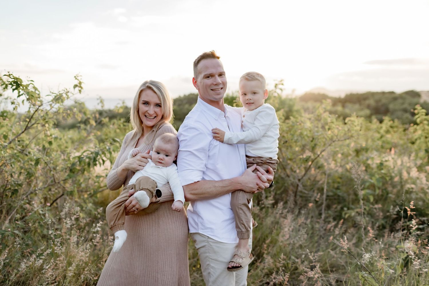 A loving family portrait captured outdoors in a natural setting during golden hour.