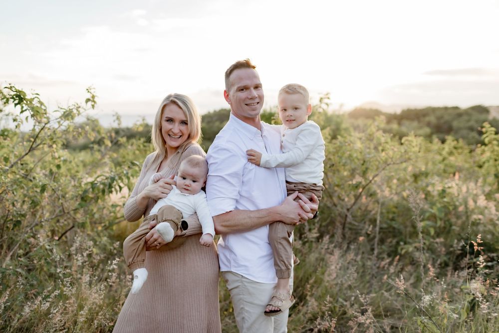 A loving family portrait captured outdoors in a natural setting during golden hour.
