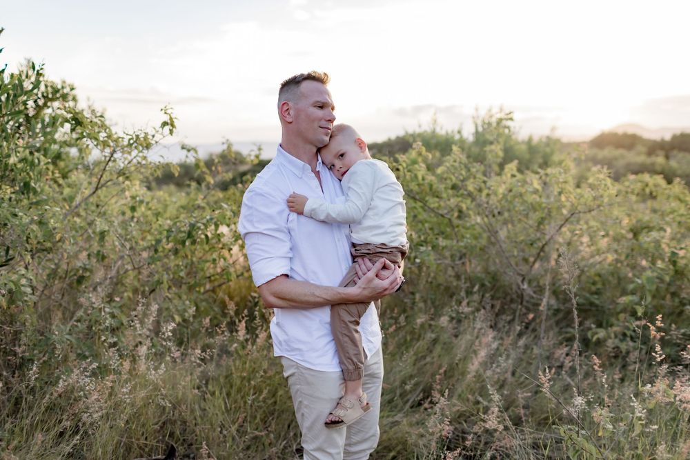 A touching moment between parent and child against a backdrop of wild vegetation.
