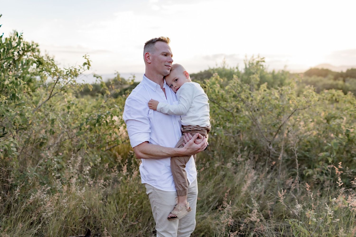 A touching moment between parent and child against a backdrop of wild vegetation.