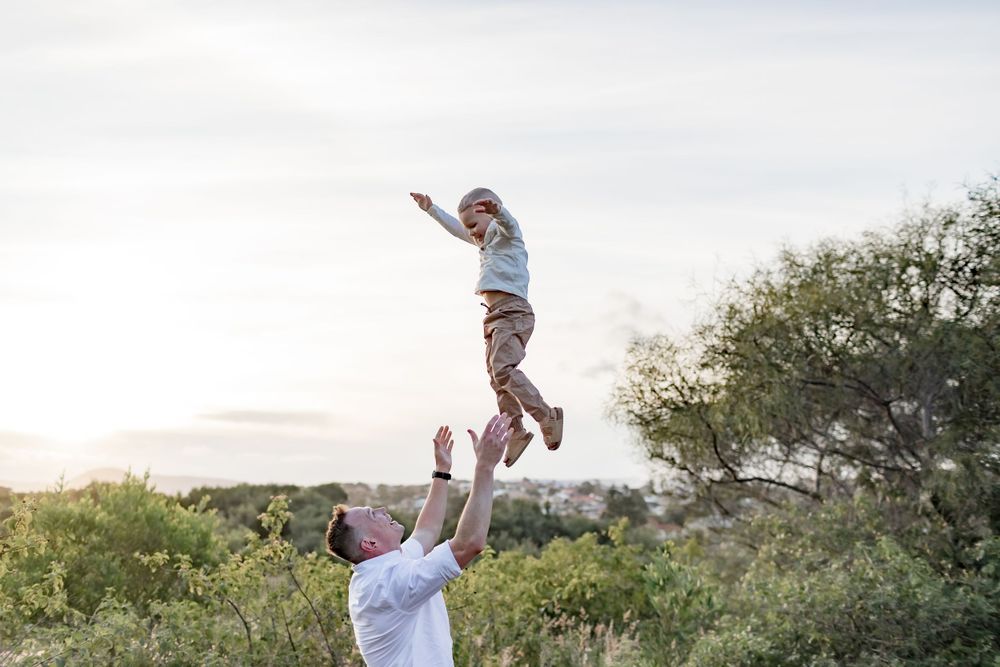 Joyful outdoor scene of lifting and playing in a natural setting at sunset.