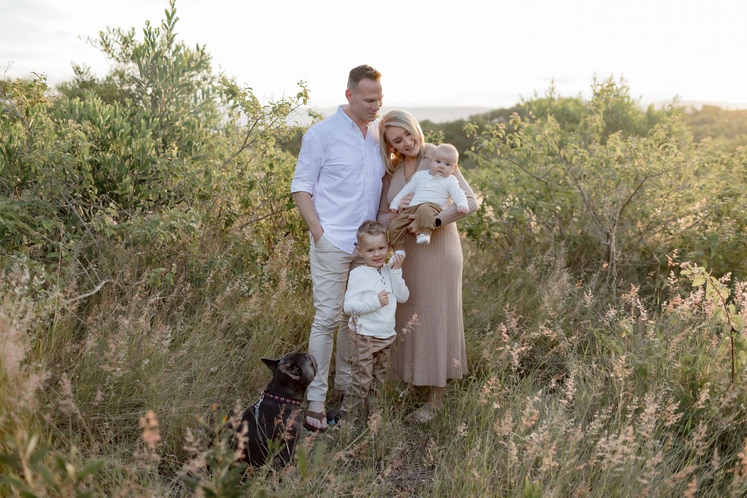 Sunset family portrait in natural field setting with dog.