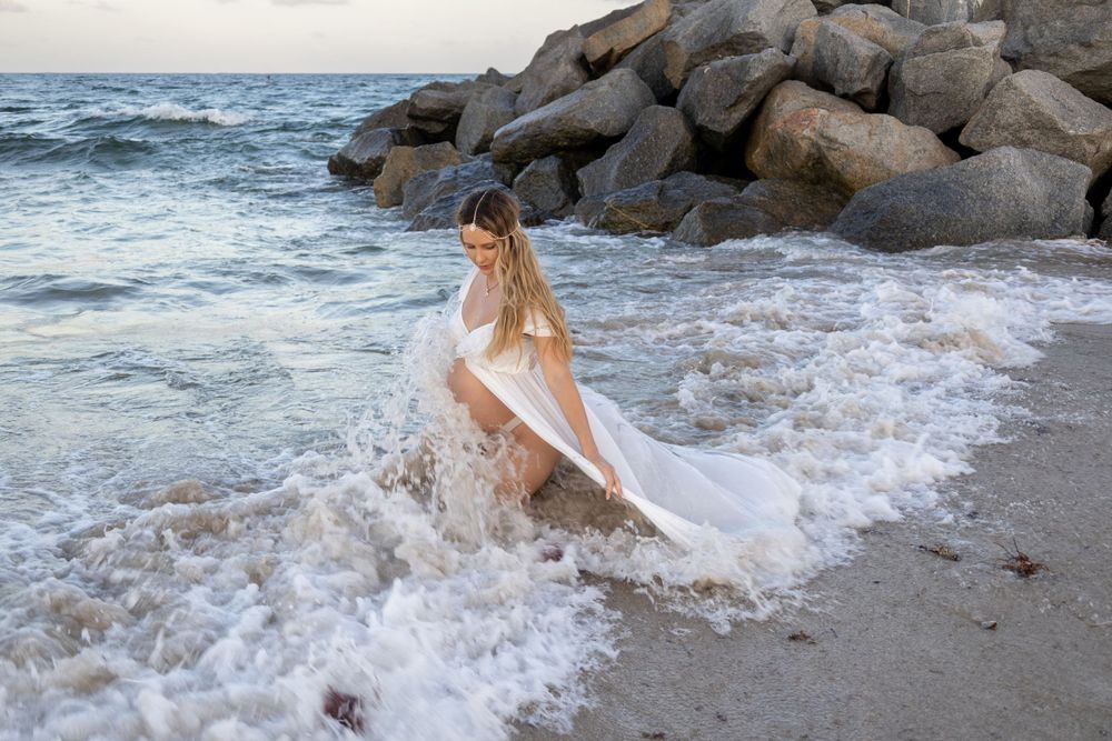 gorgeous Maternity shoot with flowy dress and giant rocks at Fort Lauderdale Beach during sunset, taken by Wanderlust Studios