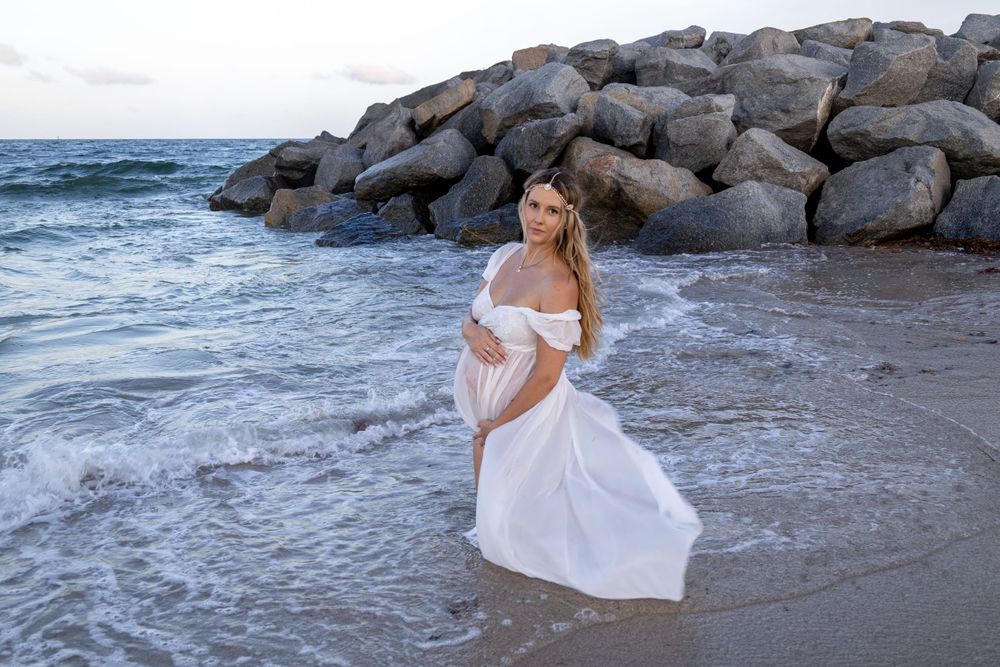 gorgeous Maternity shoot with flowy dress and giant rocks at Fort Lauderdale Beach during sunset, taken by Wanderlust Studios