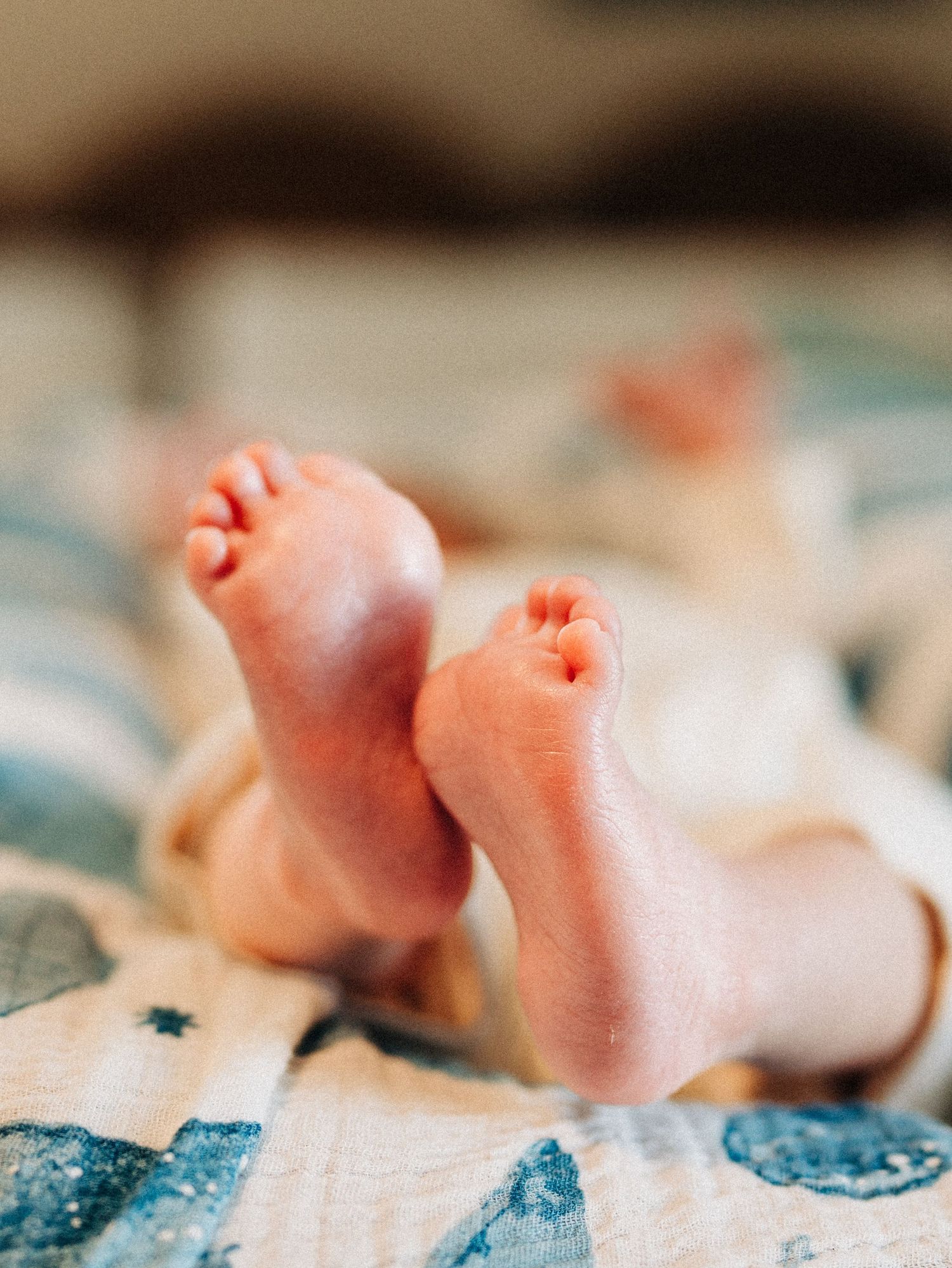 Small hand holding onto a red and blue toy teething ring against a blurred background.