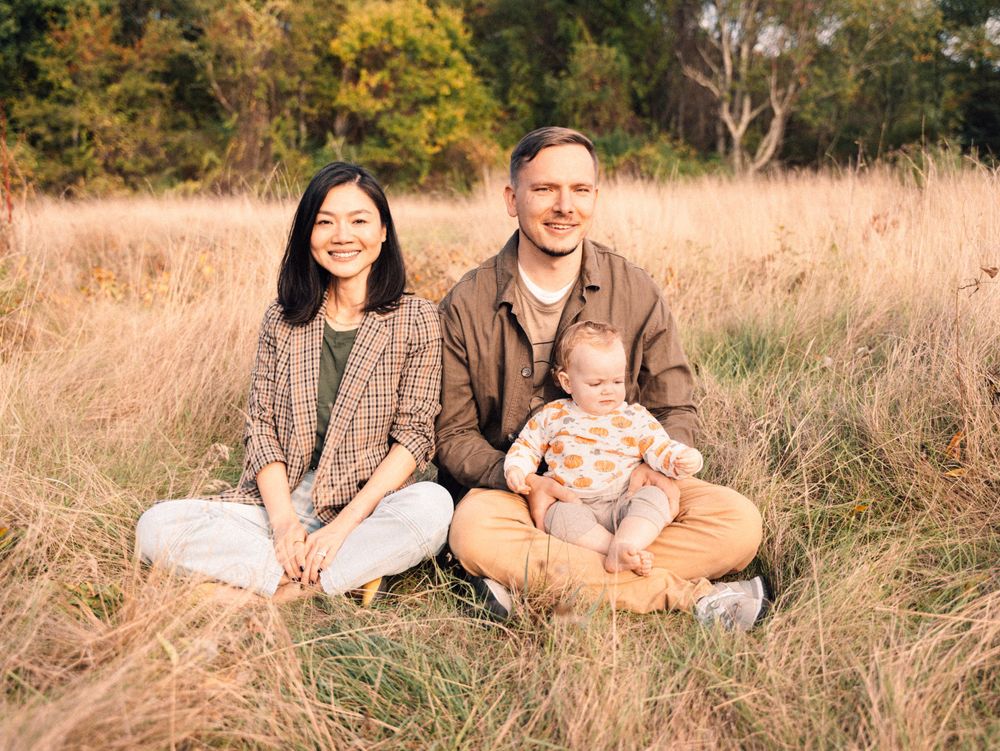 Relaxed family portrait session in tall grass during golden hour.