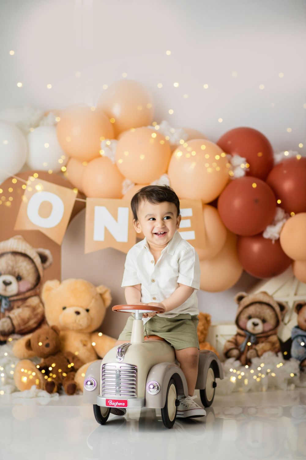 First birthday scene with vintage ride-on toy and teddy bear decorations against balloon backdrop.