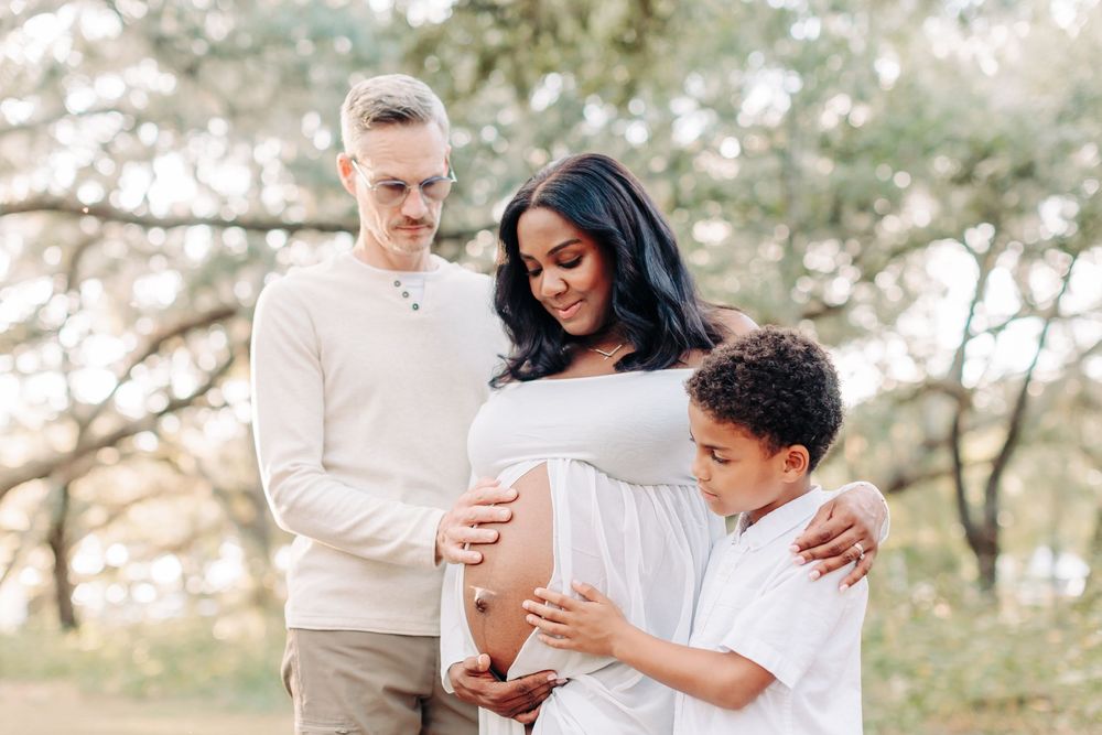 Expecting mom in white dress with her husband and son holding the belly during an outdoor Orlando maternity photo session