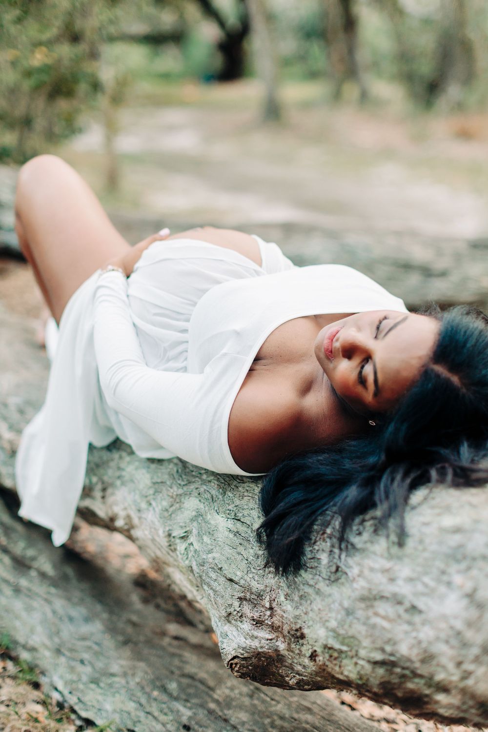 Outdoor maternity photo session with expecting mom to be laying down holding her belly