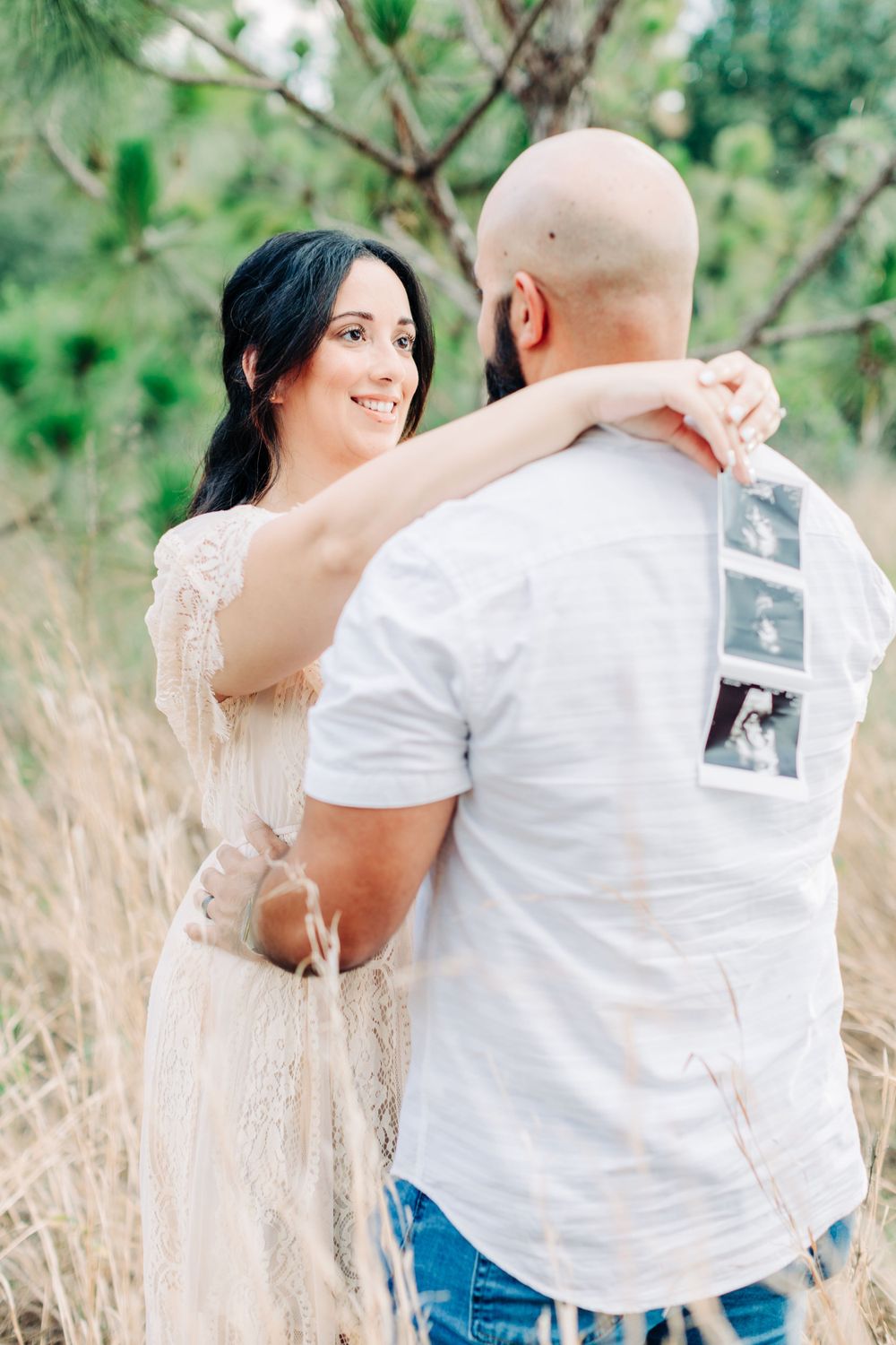 Hugging couple announcing their pregnancy with an ultrasound scan during maternity session in Orlando