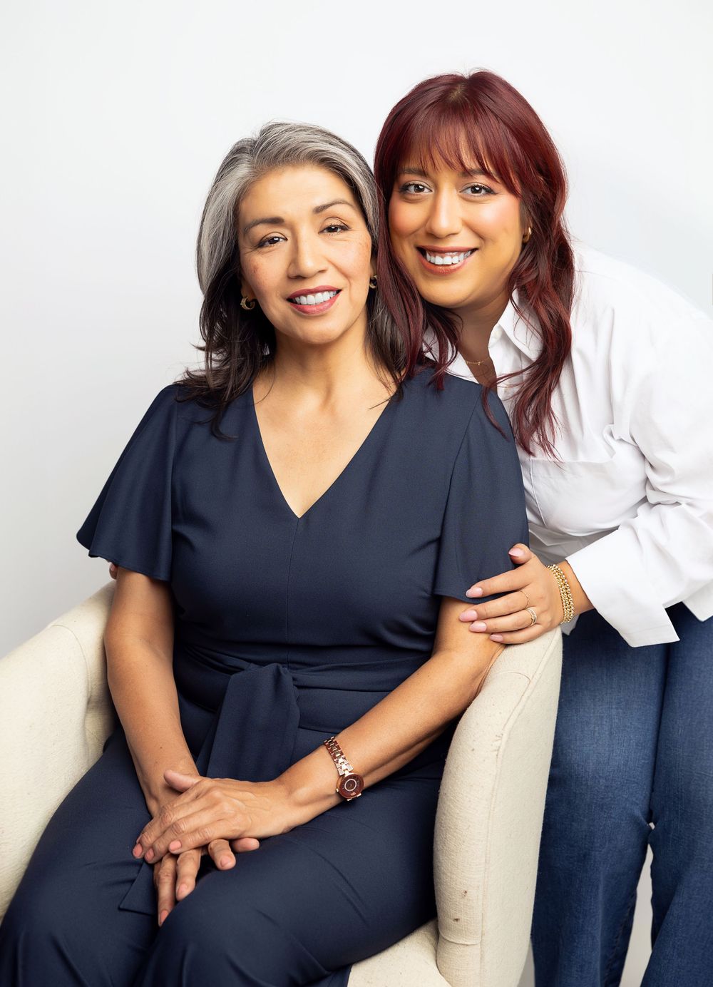 Two women in contrasting outfits sharing an affectionate moment in studio setting.