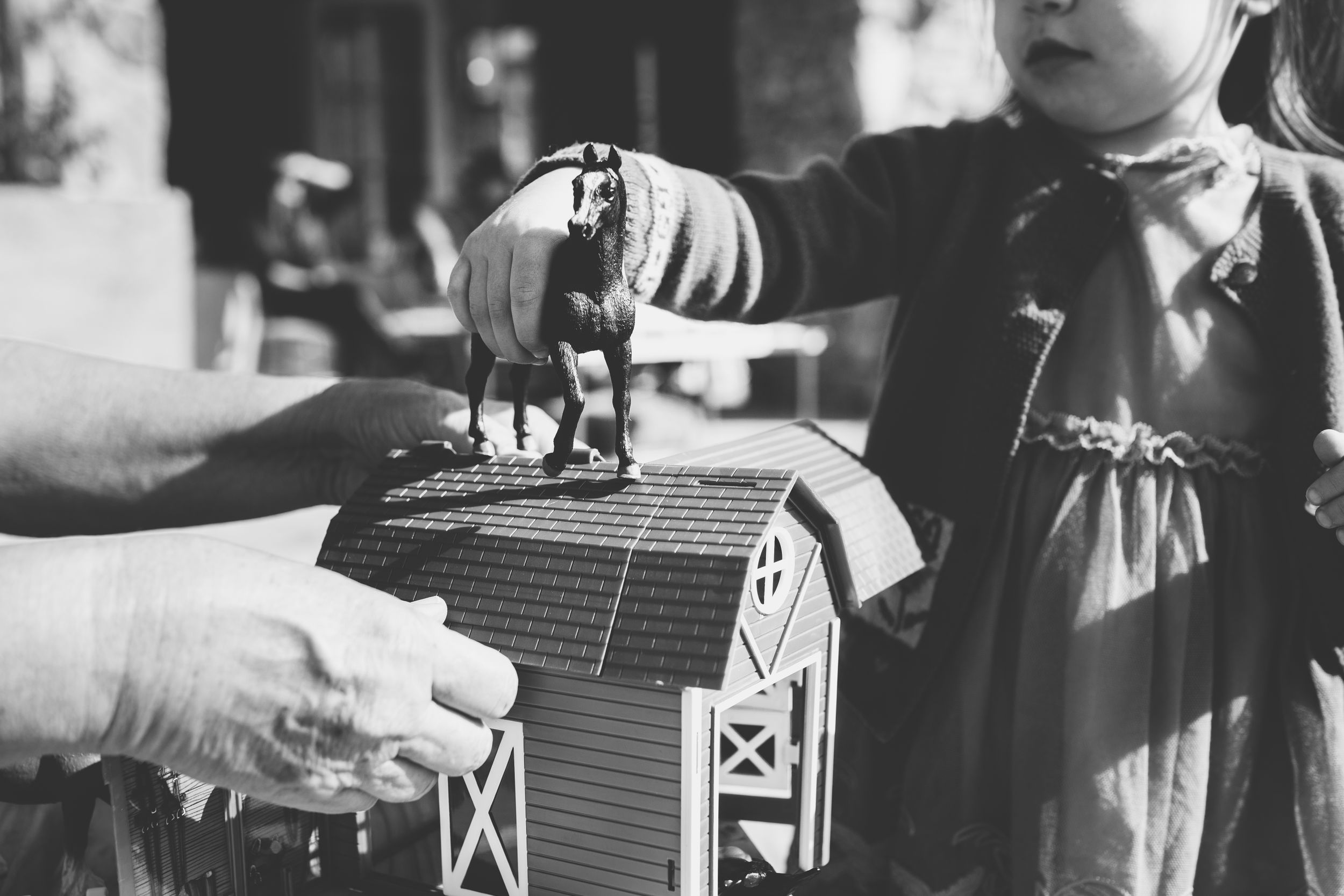 Vintage black and white photo showing hands operating an old toy barn playset.