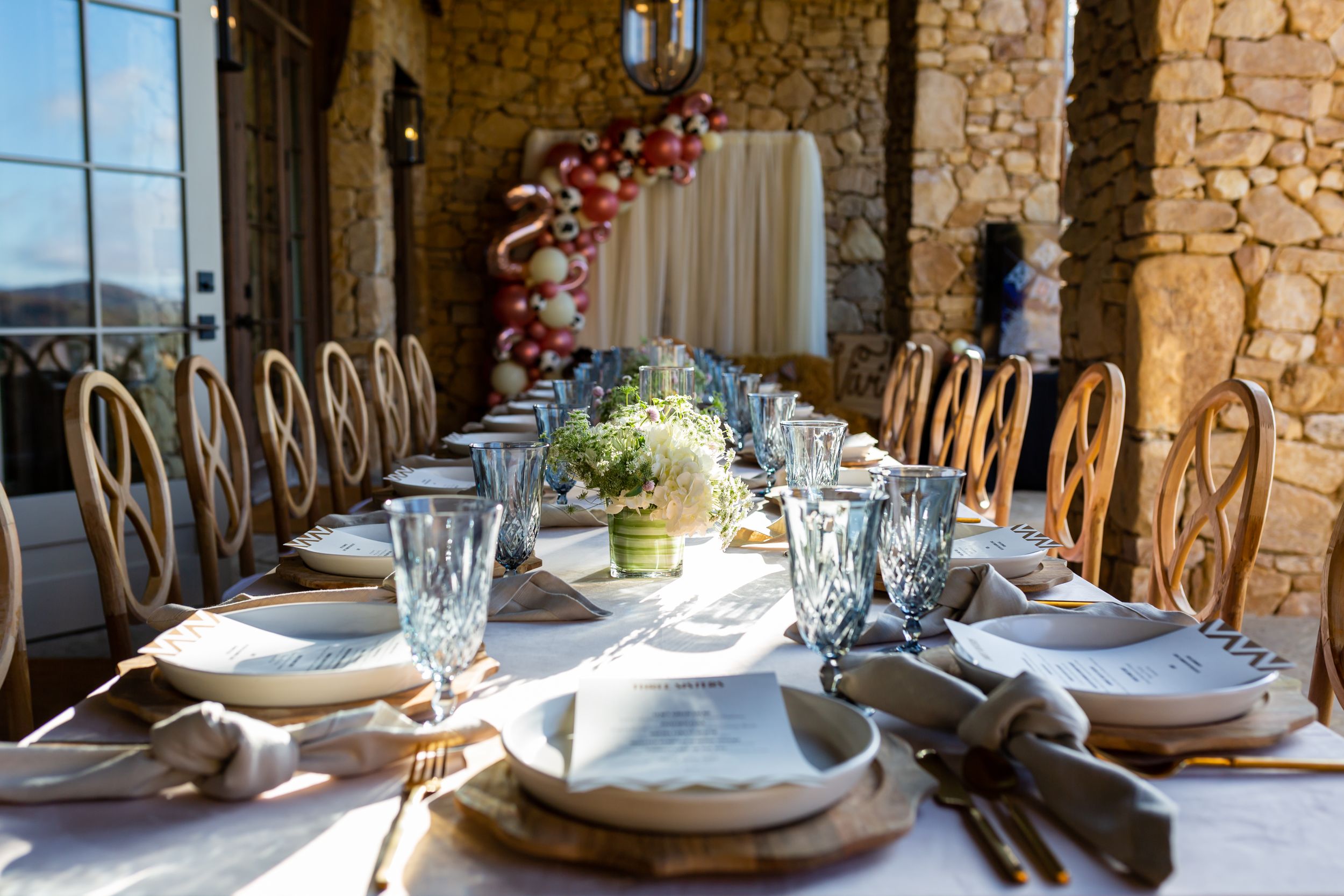 Elegant dining table setup with golden chairs and floral centerpiece in rustic venue.