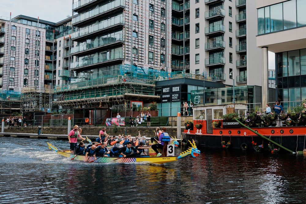 Dragon boat teams race across the harbor during a competitive festival event at a waterfront development.