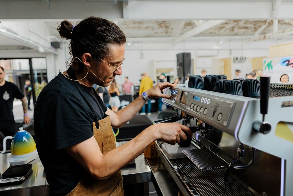 Barista operates professional espresso machine in industrial workspace.