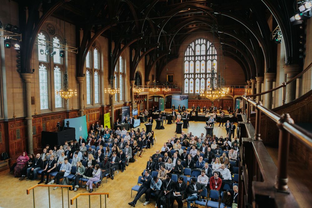 Overhead view of conference attendees seated in rows within a grand historic hall with vaulted ceiling.