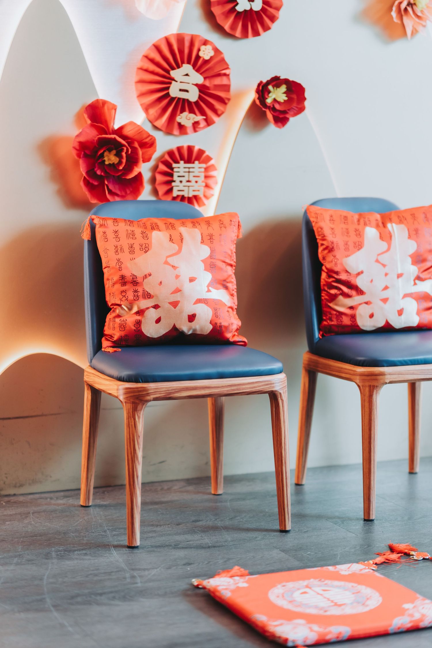 Modern orange chairs with decorative Asian-inspired pillows and paper fan decorations arranged in a row.