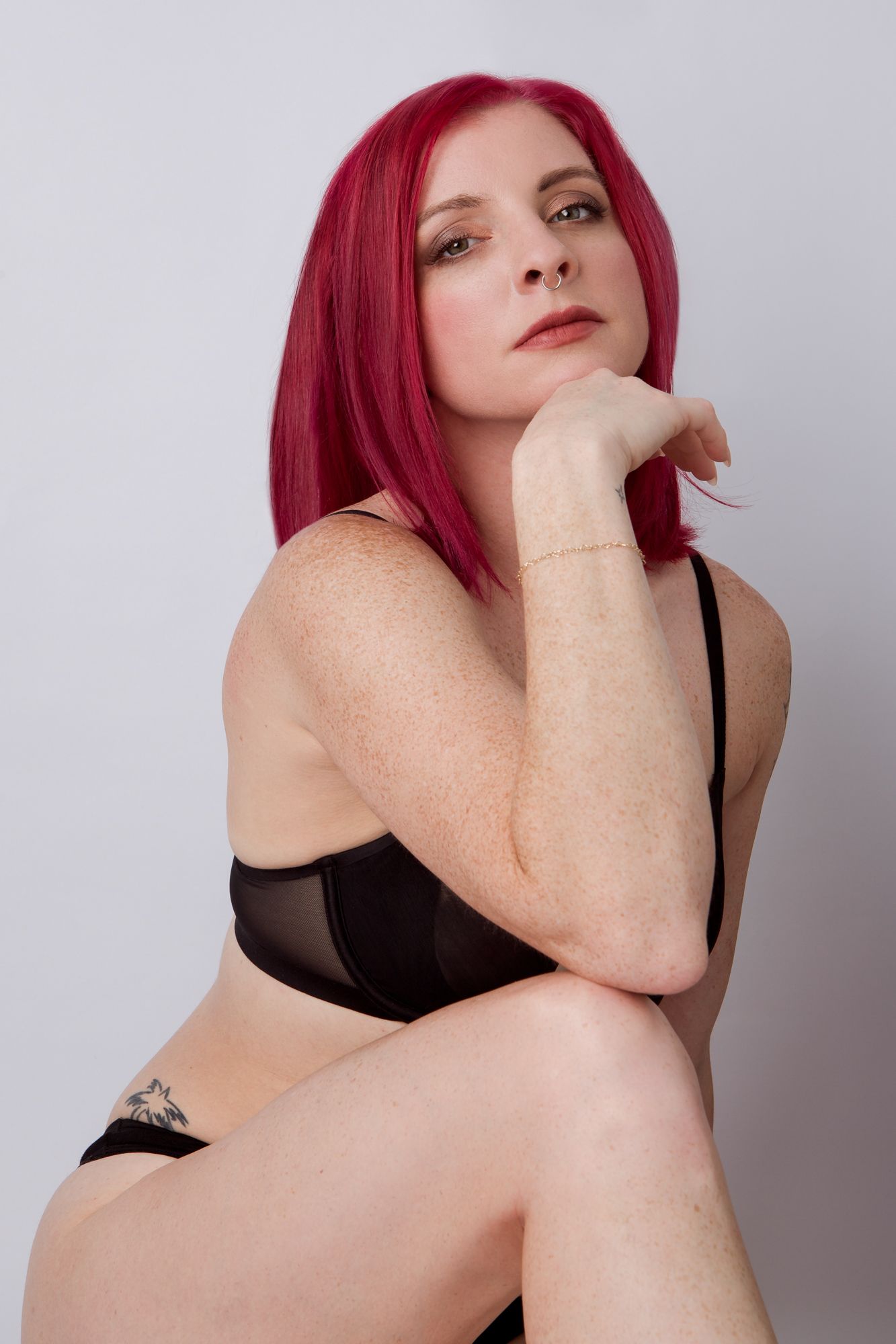 A series of artistic portraits showing a figure with vibrant red hair posing expressively against a light gray backdrop.