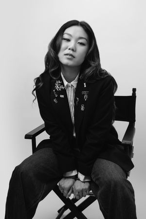 Black and white fashion photo series showing model in dark blazer and pants striking dramatic poses against white backdrop.