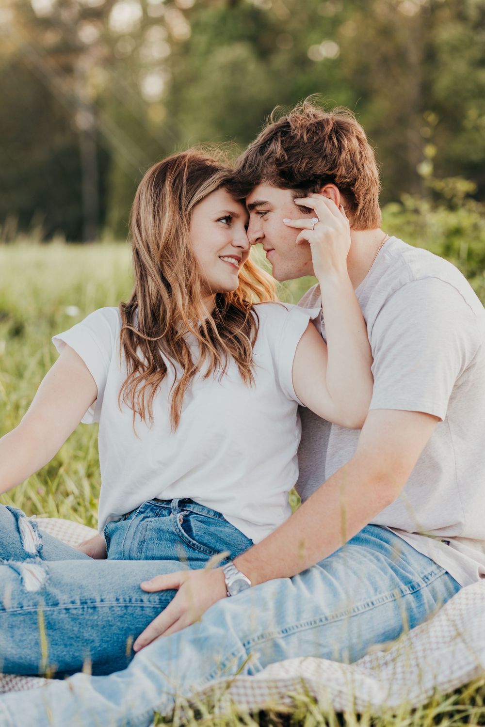 a couple sitting in the field hugging with jeans and tshirts on