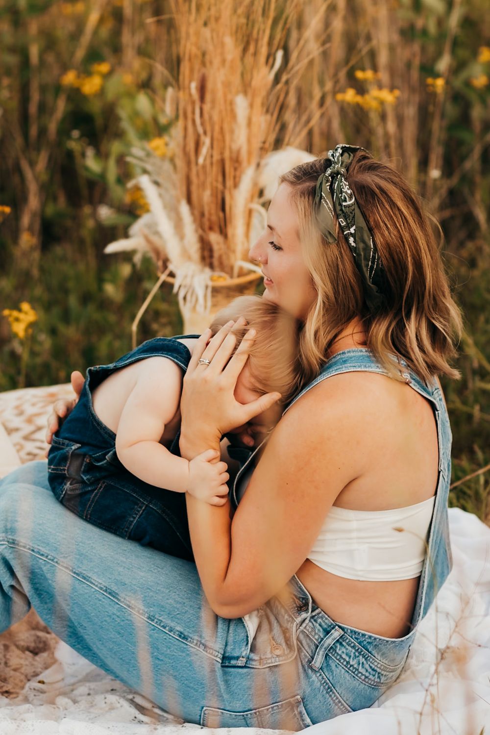 mom in overalls sitting in a field holding her baby boy