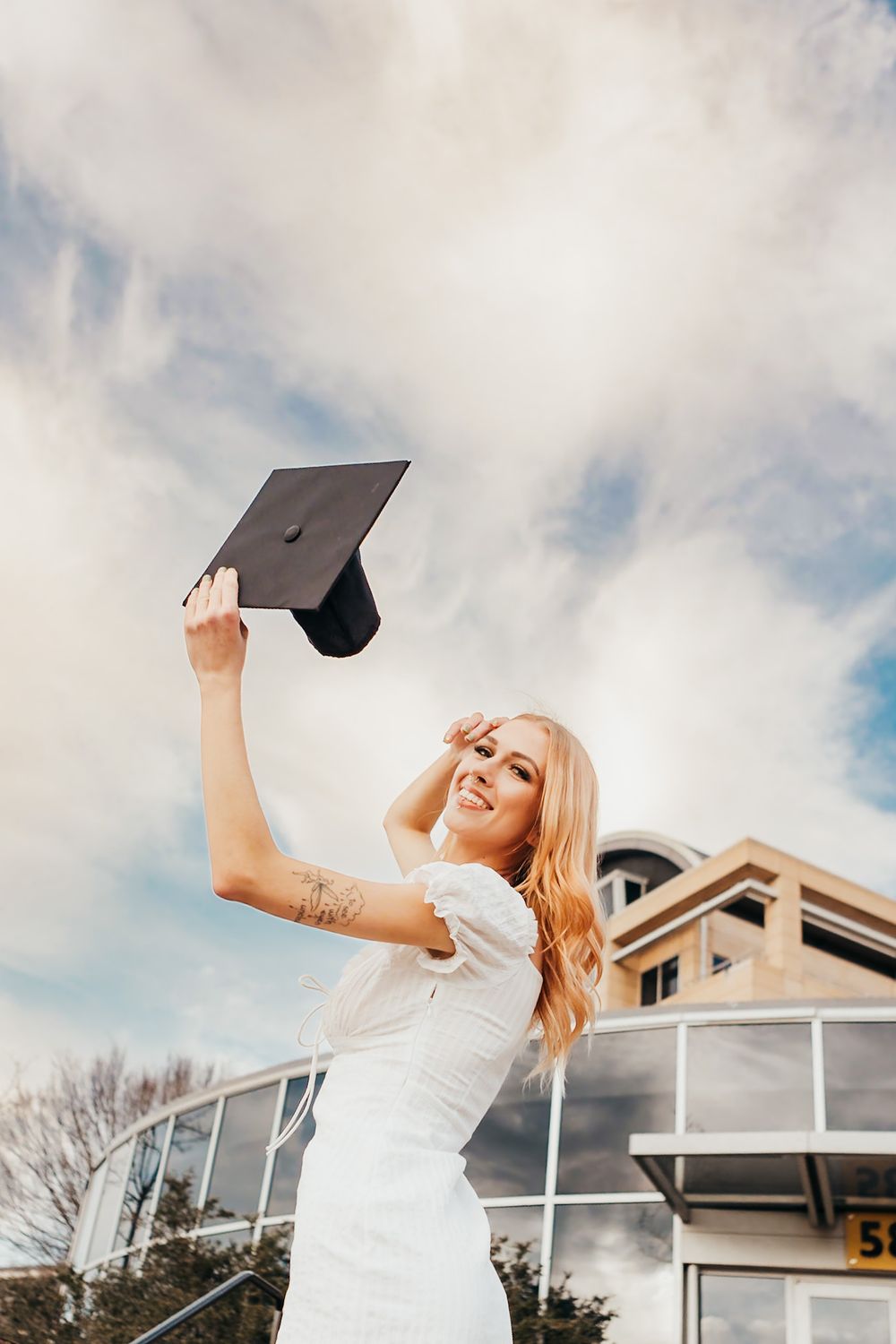 a girl in front of kennesaw college holding her cap in the air.