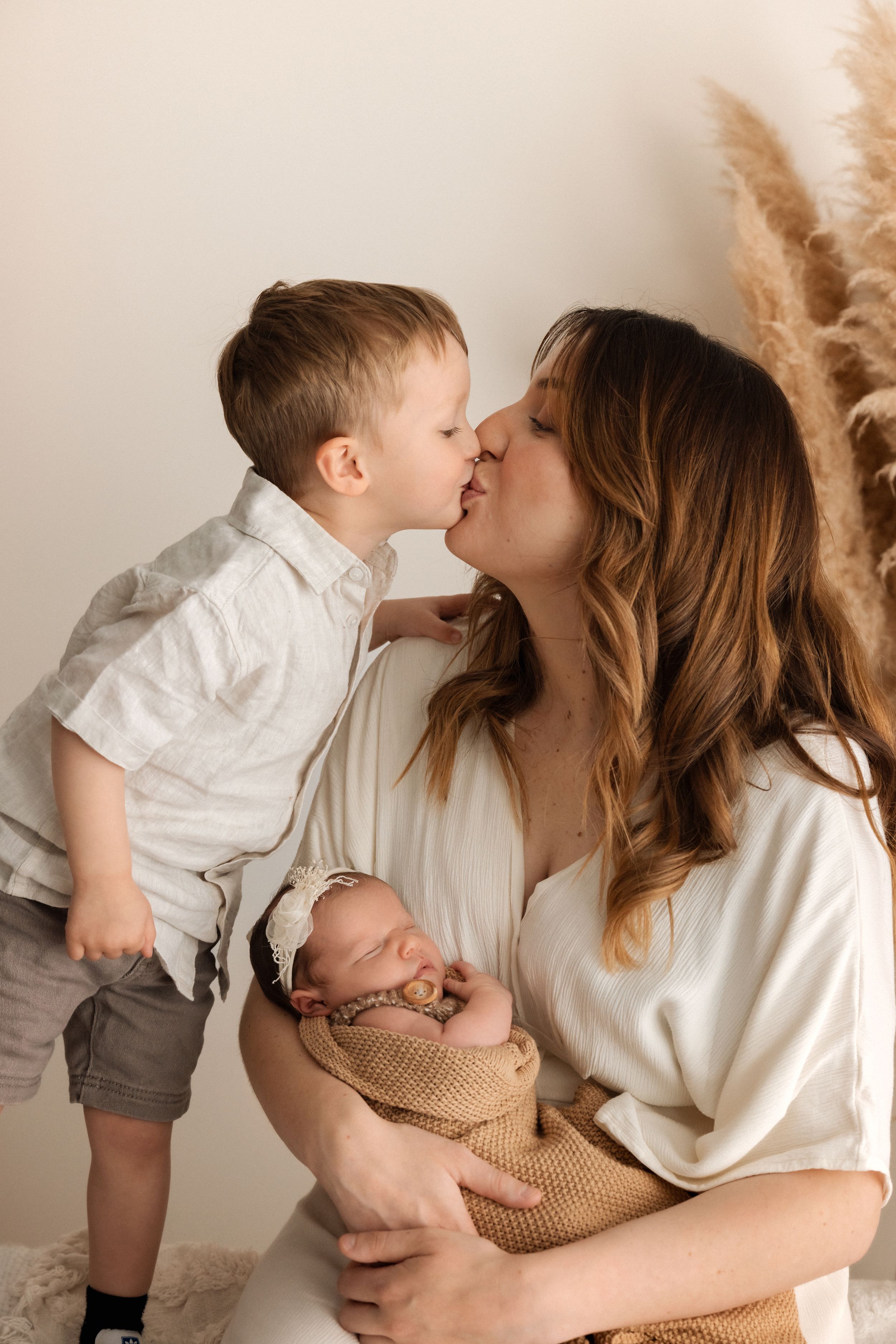 A tender family moment captured in a series of sweet interactions against a neutral backdrop.