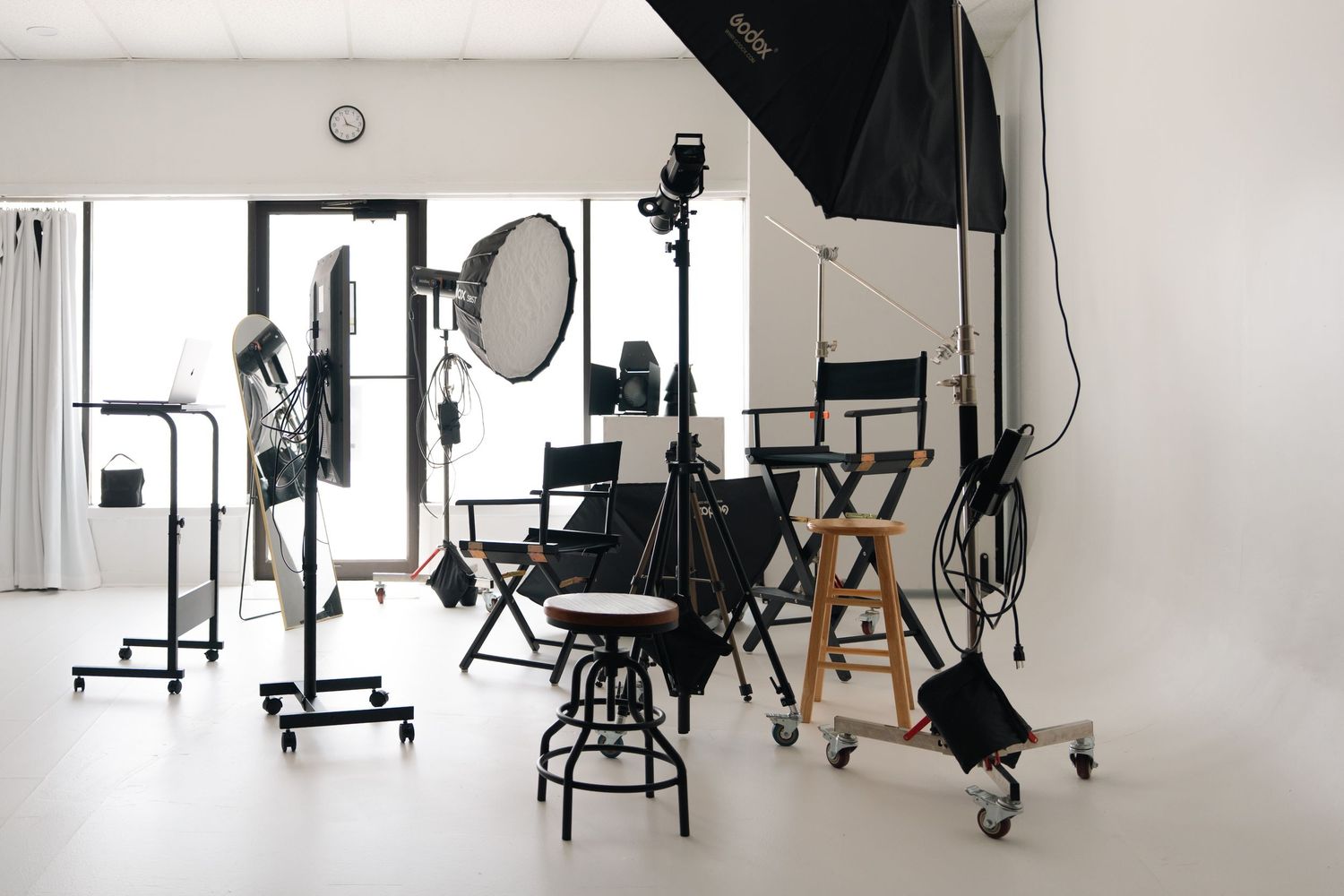 Professional photography studio with Godox strobe lights, softbox, and posing stool on hardwood floor.
