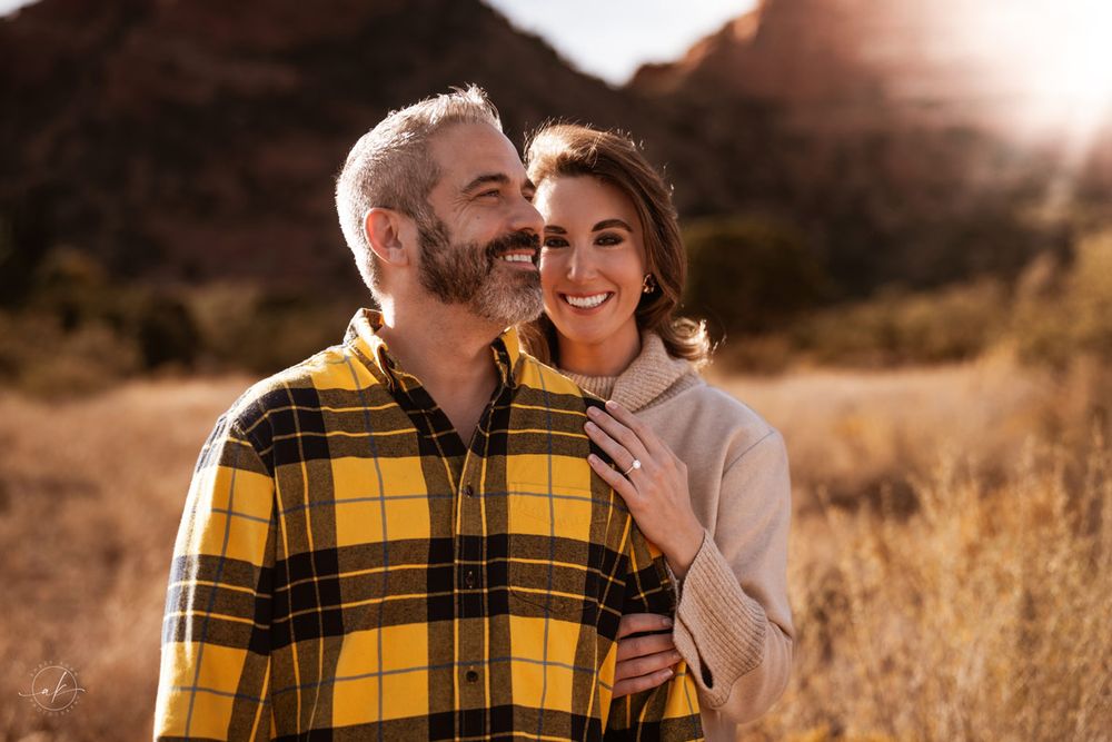 A couple shares a tender moment while wearing coordinating yellow plaid and cream sweaters outdoors.