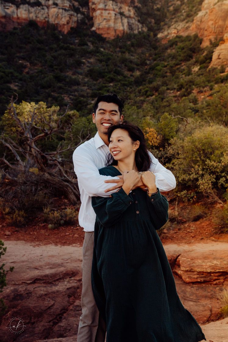 A couple shares a joyful moment together against Sedona red rock cliffs at sunset.