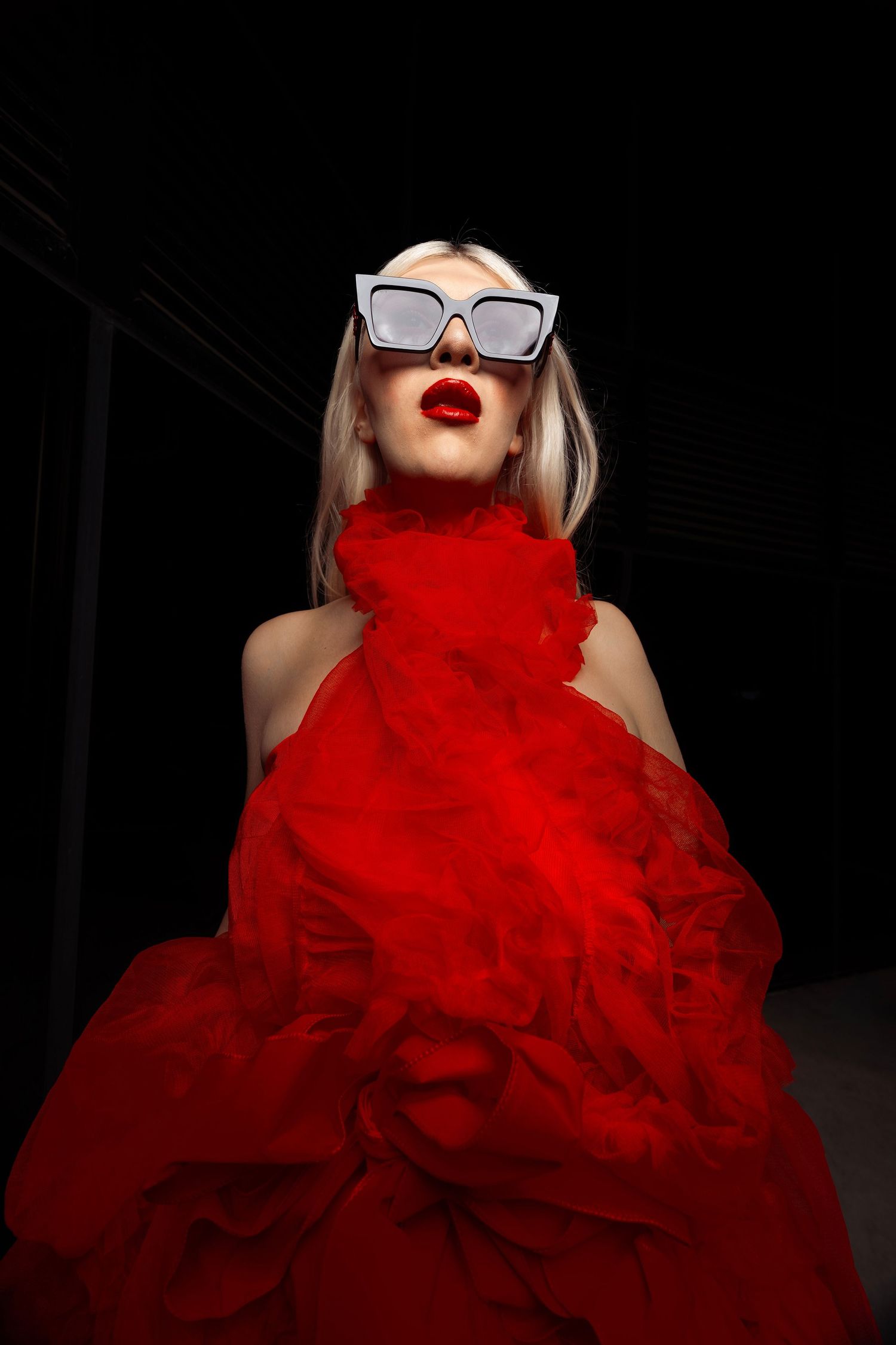 Fashion photo series featuring dramatic red tulle dress and white sunglasses against black background.