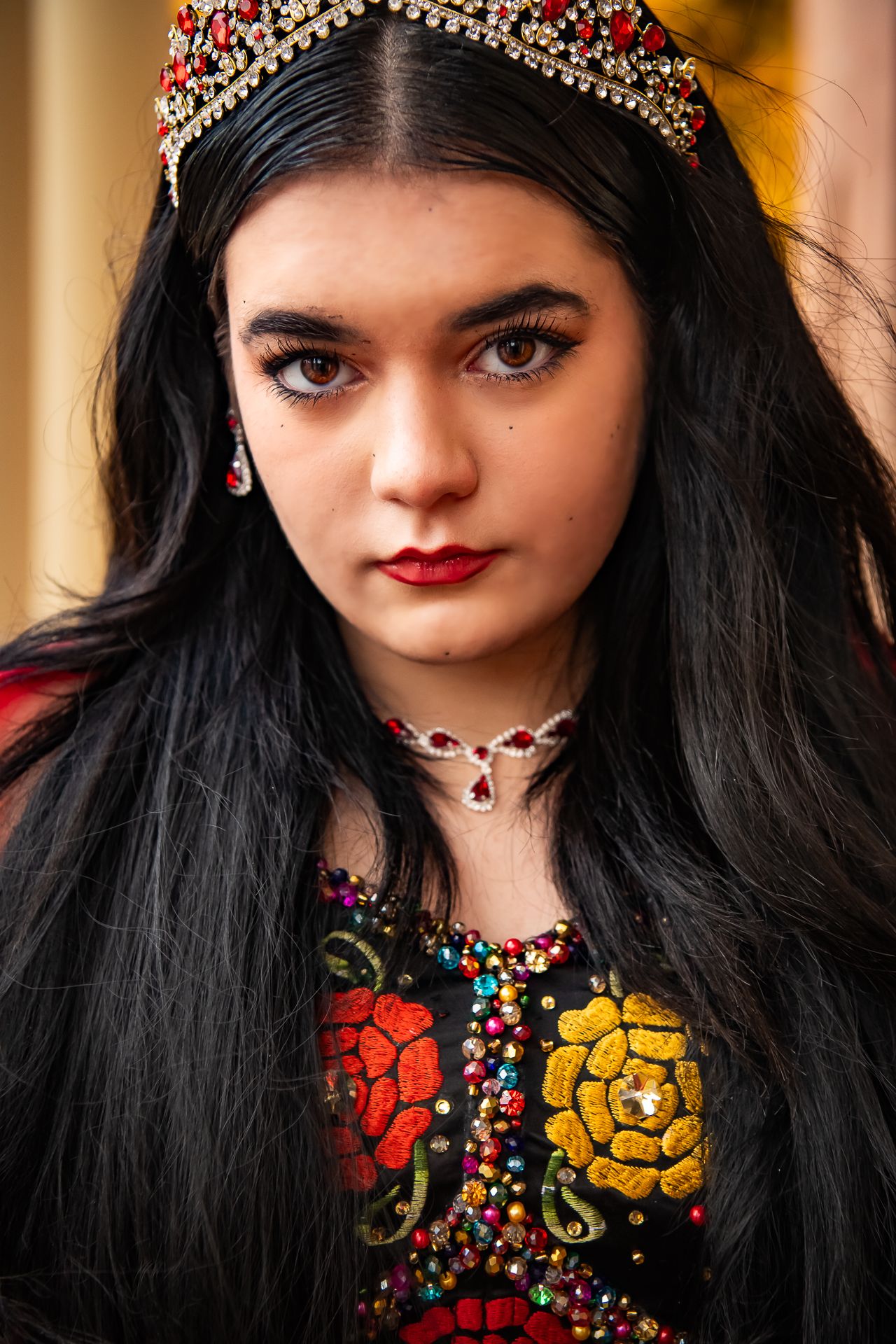 Outdoor senior portrait against autumn foliage with red maple leaves in the background.
