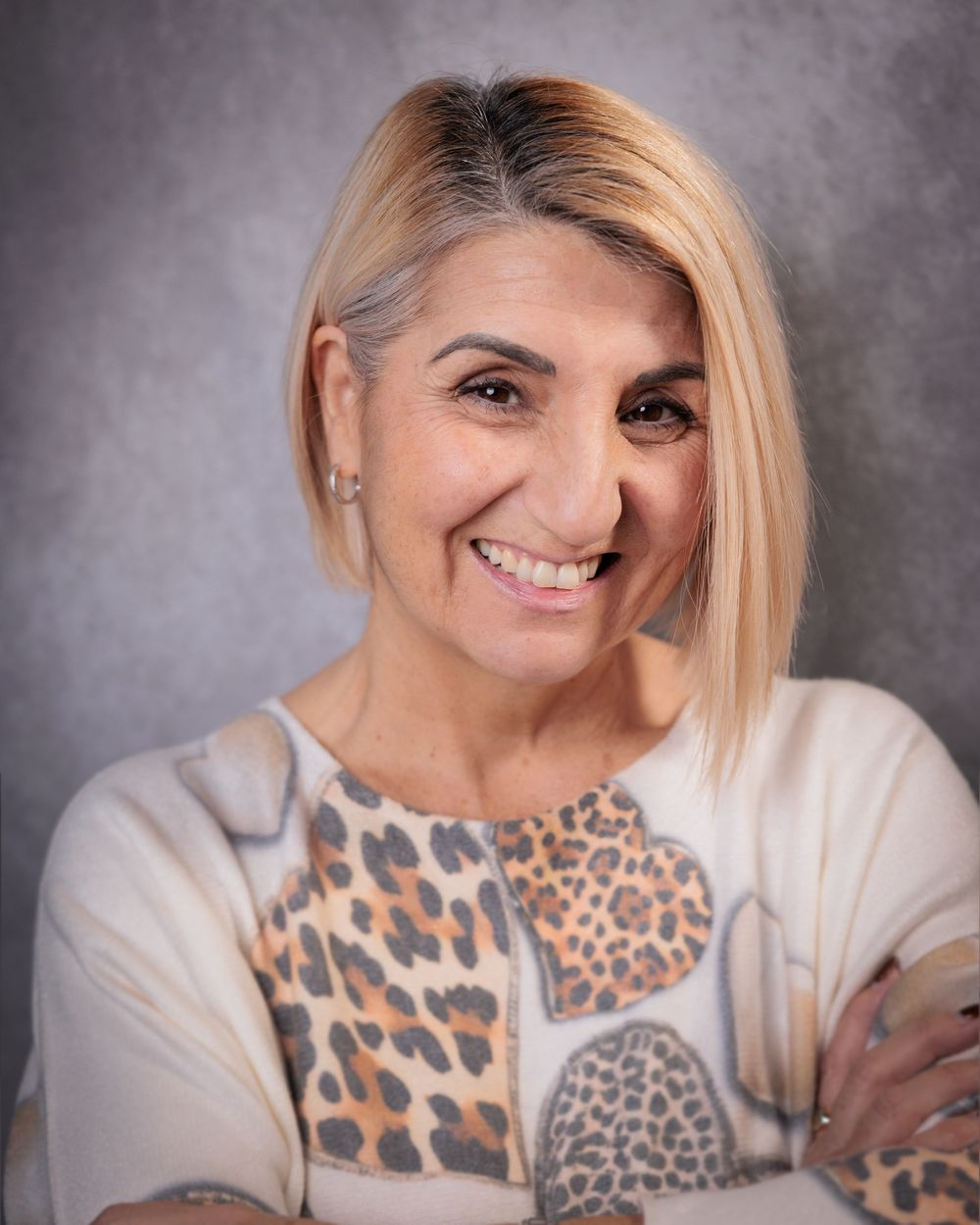 A series of studio portraits showing joyful expressions and a leopard print sweater against a gray background.