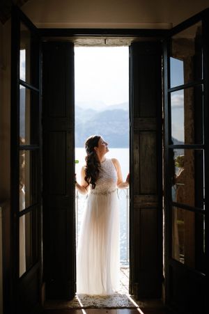 Silhouette of bride in flowing dress framed by doors of the balcon of the Casle of Malcesine, Lake Garda