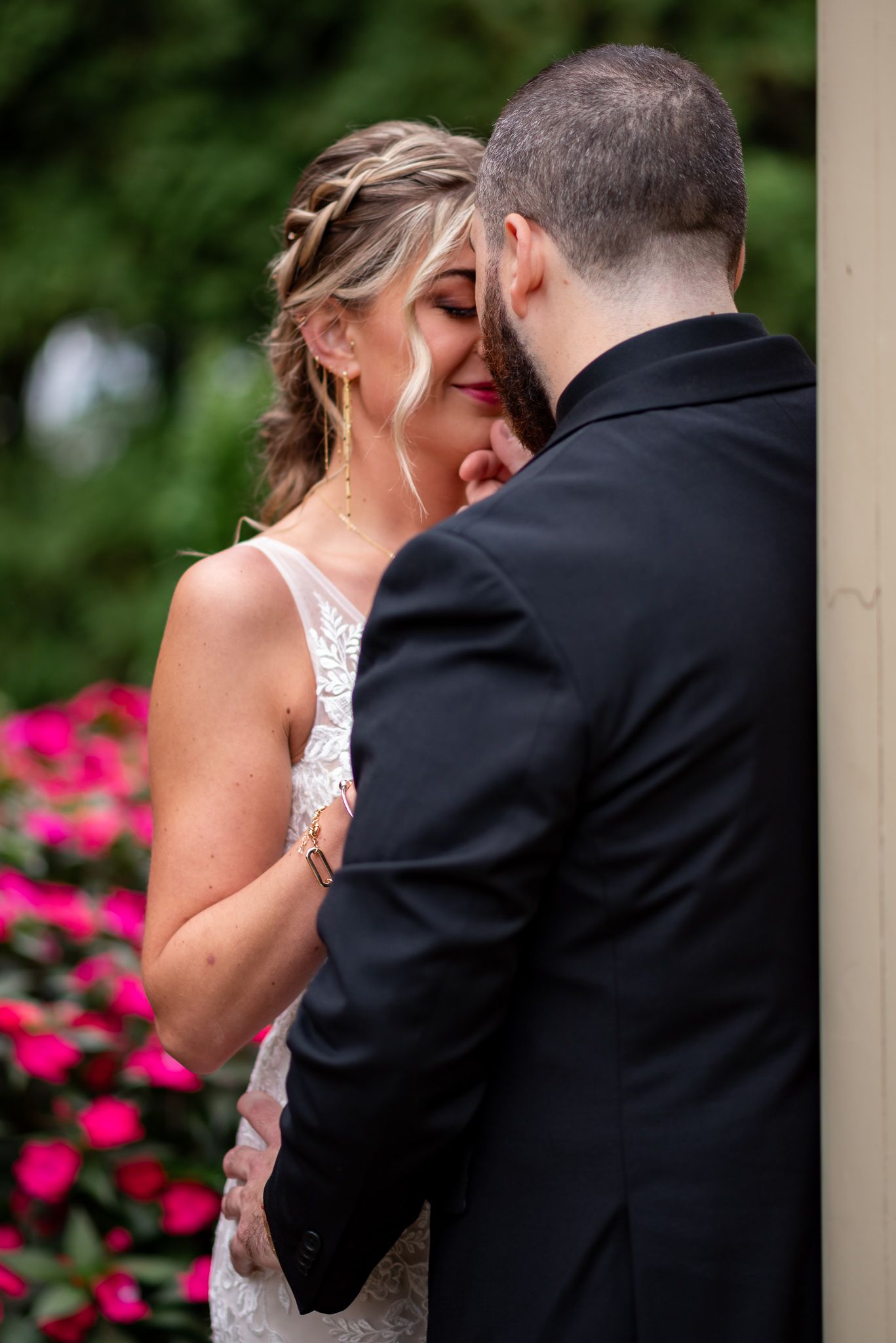 A tender moment between newlyweds as they share an intimate embrace near pink flowers during their wedding day in Connecticut.
