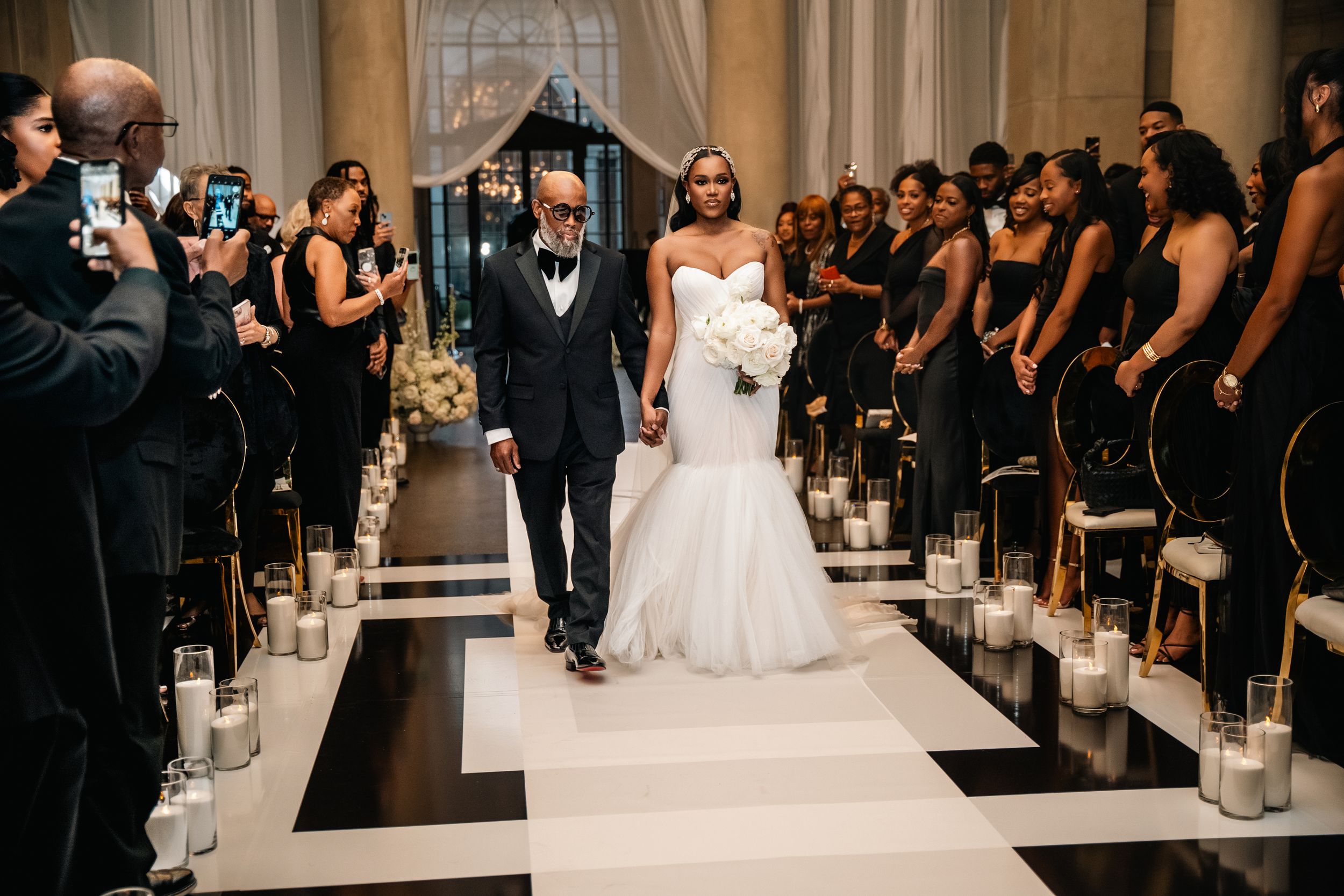 Wedding ceremony processional on black and white aisle with candle lined walkway.