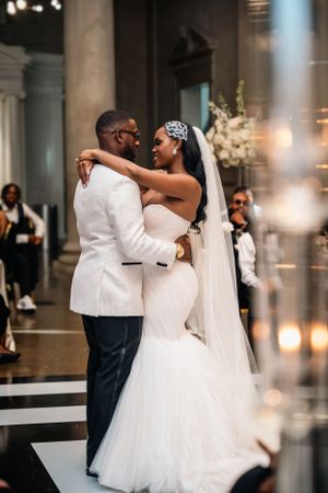 Newlyweds share romantic dance moment on black and white checkered floor.