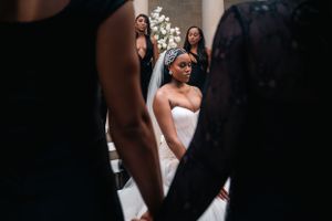 Candid moment captures bride surrounded by attendants in black dresses.