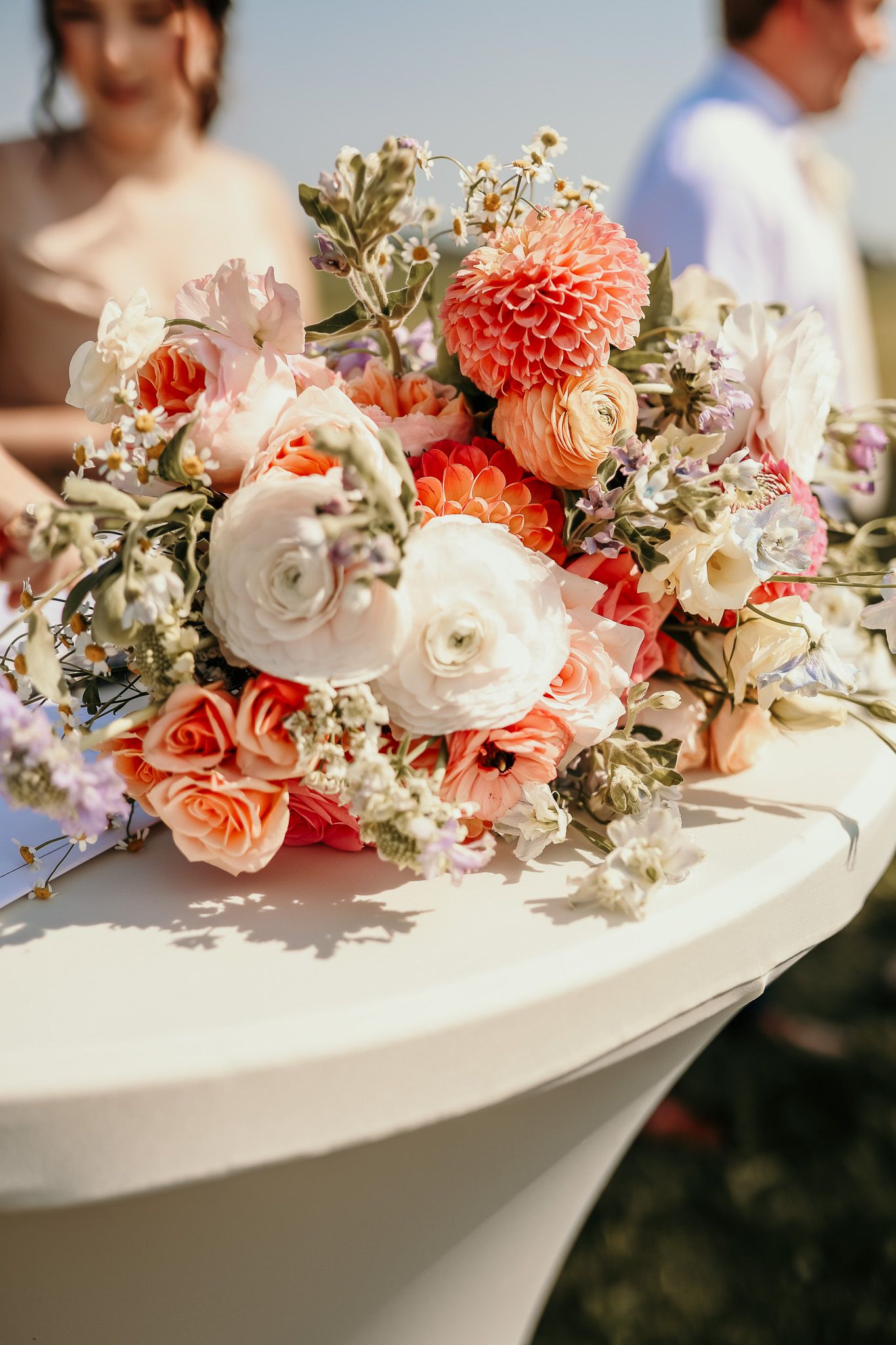 Beautiful coral and white floral arrangement with roses and dahlias on a cocktail table.