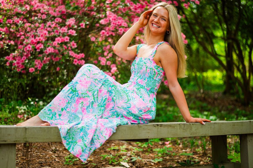 Casual outdoor portrait on wooden bench with pink azalea flowers.