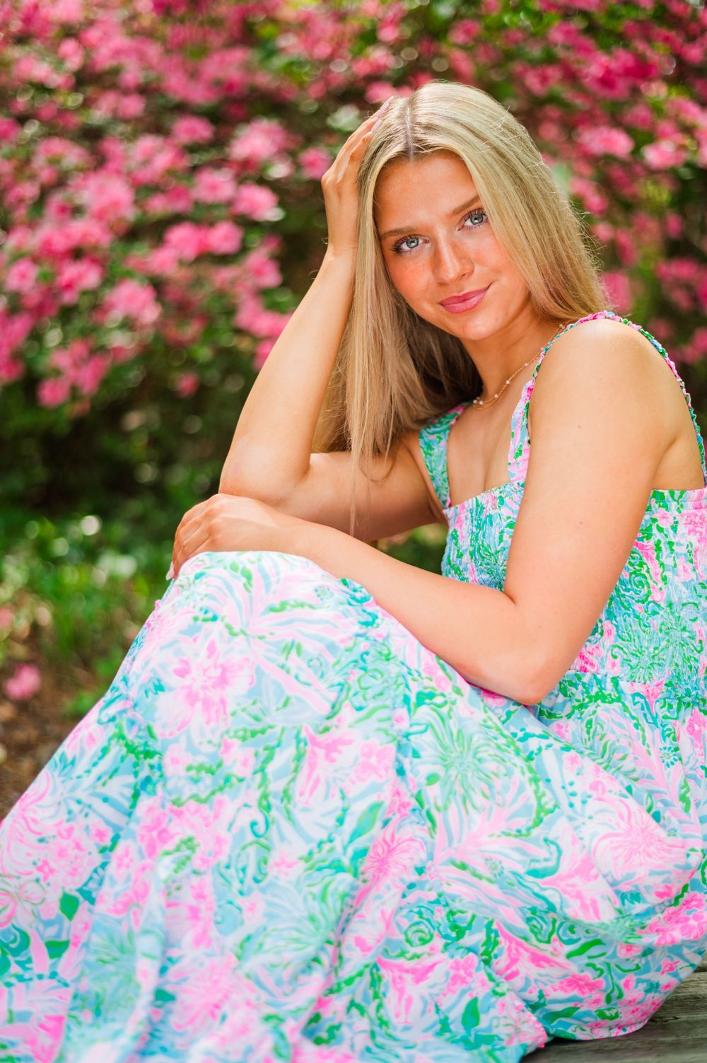 Spring portrait with pink azalea flowers in floral print dress.