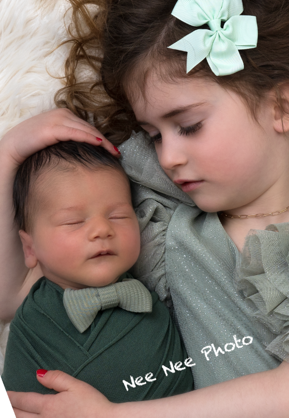 Young girl with mint bow tenderly holds sleeping newborn in green bow tie wrap in professional portrait photo. Embracing Life’s Beauty