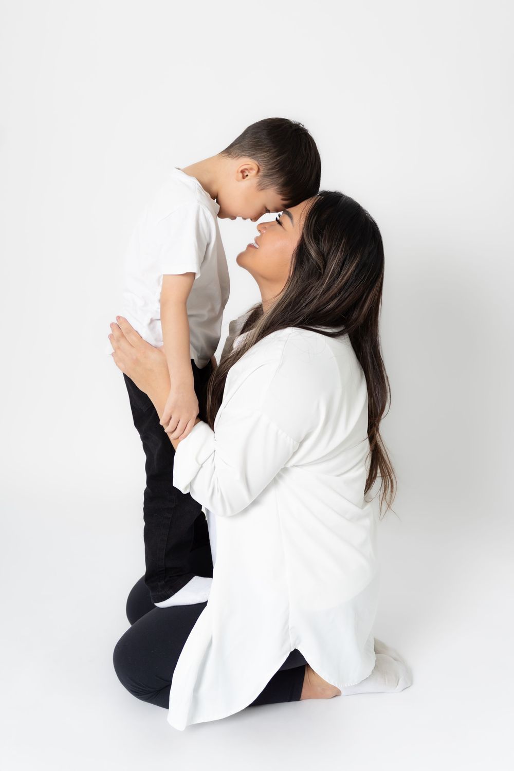 An intimate portrait of a tender embrace between parent and child against a white backdrop.