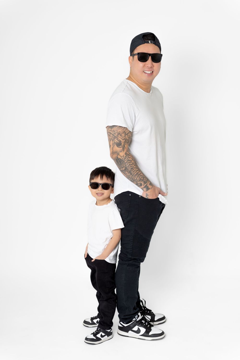 Parent and child in coordinated outfits posing playfully against white background.