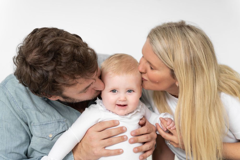 A series of four tender family moments showing parents sharing affectionate kisses and embraces with their baby.